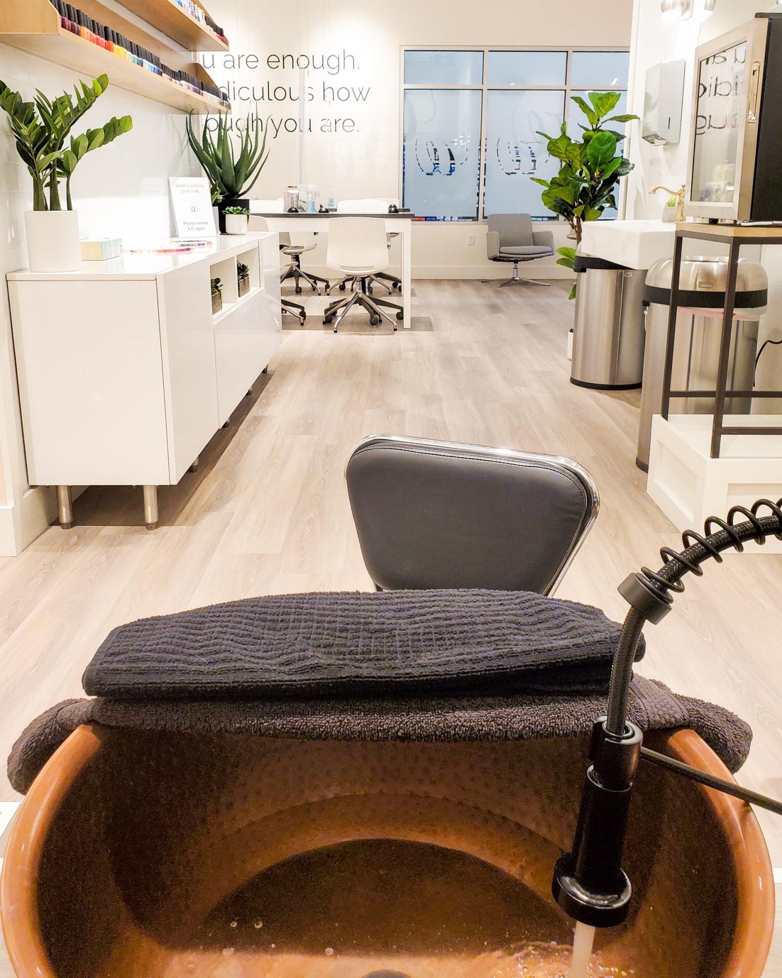 The copper bowls at the W Nail Bar. Beyond the bowl you see fake plants and a manicure station.