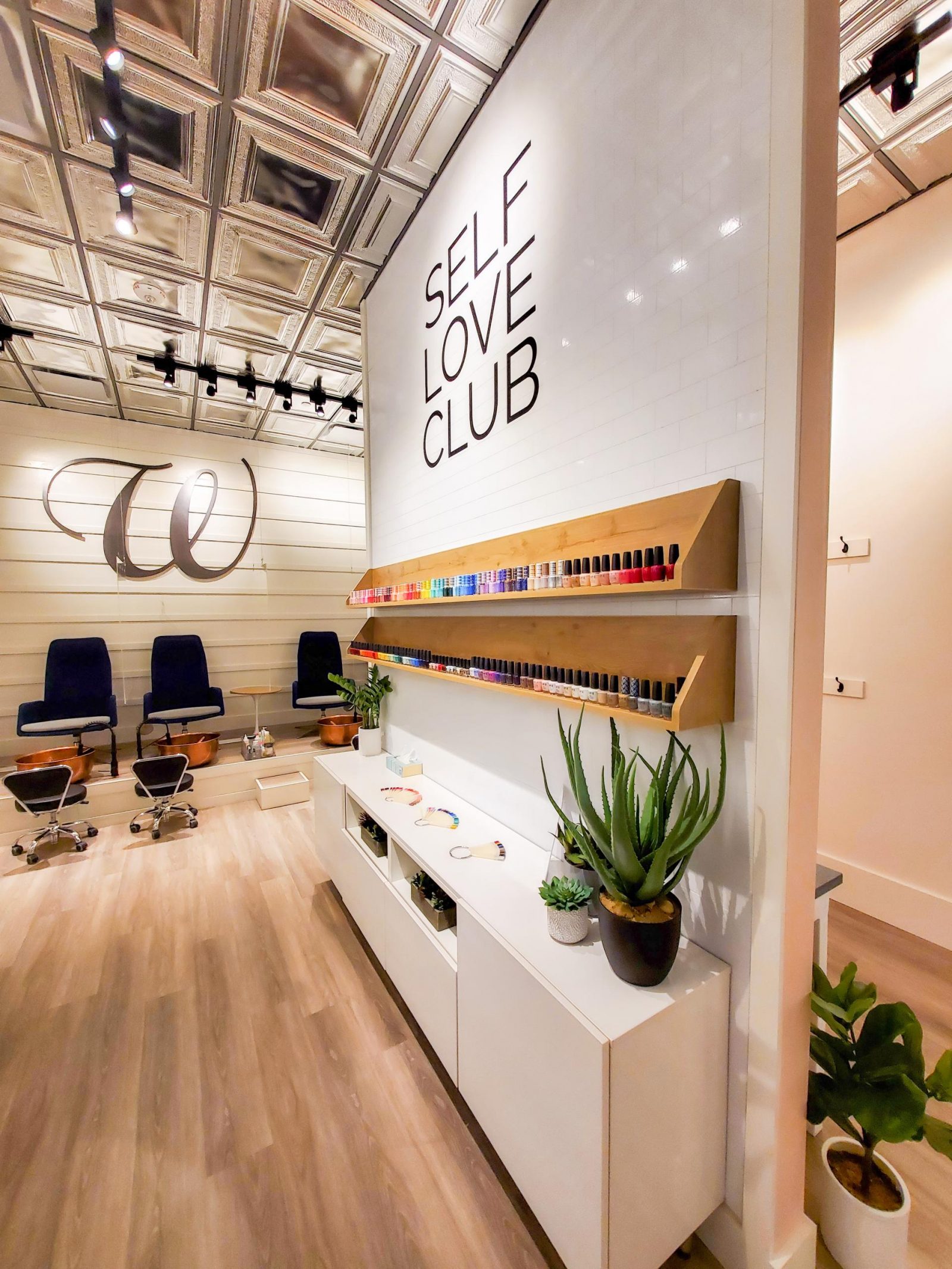 The assortment of nail polish colors offered at the W Nail Bar in the Quad Cities. Above the nail polishes is wall art that says "Self Love Club"